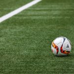 Cancha de fútbol donde se aprecia línea blanca y pelota.
